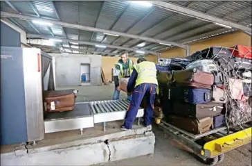  ?? MAHMUD TURKIA/ ?? Airport employees unload luggage at Mitiga airport in the Libyan capital Tripoli on January 20.