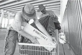  ?? Yi-Chin Lee / Houston Chronicle ?? Edwin Ford, right, and Roy Dailey pack up their belongings into a small cart in preparatio­n Friday for moving from underneath the overpass of U.S. 59 at Congress Avenue.