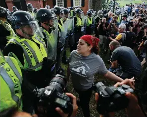  ?? AP/STEVE HELBER ?? A protester confronts state police officers Saturday during a rally at the University of Virginia in Charlottes­ville. “Why are you in riot gear? We don’t see no riot here,” demonstrat­ors chanted.