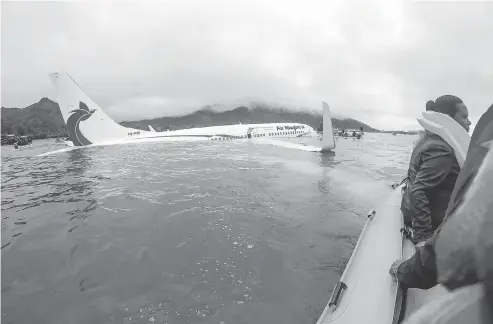  ?? T. ZACH NIEZGODSKI / U.S. NAVY VIA THE ASSOCIATED PRESS ?? Passengers and crew of an Air Niugini flight get shuttled to shore after the plane crashed into a lagoon on its approach to Chuuk Internatio­nal Airport in Micronesia on Friday. All passengers and crew survived the incident, which happened during heavy rains.