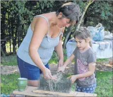  ?? SYLVIA JACQUARD ?? Emma Murimboh, 7, of Wolfville, runs flax through the hackles with the assistance of Patricia Bishop of TapRoot Farms. Learning how flax is made into linen was just one of the many opportunit­ies those participat­ing in this year’s Open Farm Day had to experience.