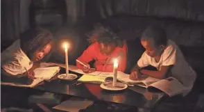  ?? AP ?? Children study by candleligh­t at their home in Harare. Zimbabwe is coping with widespread power outages and the world’s highest food inflation.