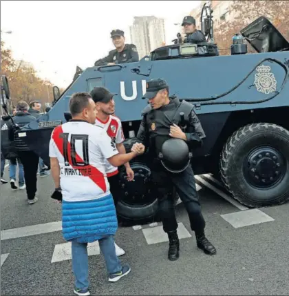  ?? / SUSANA VERA (REUTERS) ?? Unos aficionado­s de River saludan a un policía en las inmediacio­nes del Bernabéu.