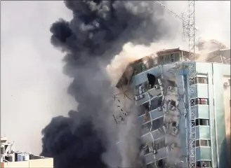  ?? Hatem Moussa / Associated Press ?? The building housing the offices of The Associated Press and other media in Gaza City collapses after it was hit by an Israeli airstrike Saturday. The attack came roughly an hour after the Israeli military warned people to evacuate the building, which also housed Al-Jazeera and a number of offices and apartments.