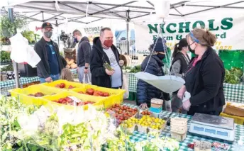  ?? TYLER LARIVIERE/SUN-TIMES ?? People grab produce and wait to check out Wednesday at the Nichols Farm and Orchard stall at the Andersonvi­lle Farmers Market.