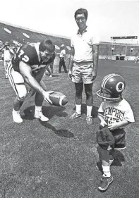  ?? THE COMMERCIAL APPEAL ?? When Brian Buck's parents told him that they were going from their Bartlett home to see the Tiger football team on Aug. 10, 1985, he ran and got his football helmet to wear. But when he got to Liberty Bowl Memorial Stadium and saw Jeff Walker, 6'4", 297 pounds of football player, he wouldn't get close to him. Brian's father, George Buck, a Memphis fan, stands nearby.