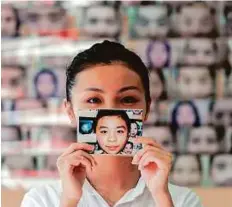  ?? AFP ?? Daisy Tse holds up a photo showing the natural shape of her eyebrows before having them plucked by a face reader.