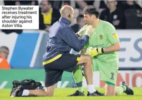  ??  ?? Stephen Bywater receives treatment after injuring his shoulder against Aston Villa.