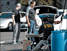  ?? REED SAXON/AP ?? Federal agents work at a downtown Los Angeles parking lot, processing suspects after pre-dawn raids Thursday.