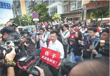  ??  ?? Wang (centre) holding a sign reads ‘Child, welcome home’, as he waits to reunite with his daughter Kang Ying.