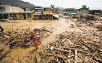  ?? Fernando Vergara / Associated Press ?? Rescuers comb through debris looking for survivors in Mocoa, Colombia. Heavy rain caused the three rivers that surround the town to rise up and surge through the city of 40,000.