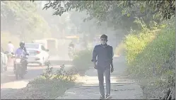  ?? SUNIL GHOSH/HT PHOTO ?? A commuter covers his face while walking on a dusty road in Sector 49. Noida’s air quality index was 254 on Monday, 242 on Tuesday and 269 on Wednesday, all in ‘poor’ category.