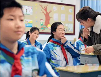  ?? Fotos de Xinhua ?? 28 de diciembre de 2021. Fan Haiyan, instructor­a de jóvenes pioneros, se comunica con alumnos en lenguaje de señas en la escuela especial de la ciudad de Yichun, en la provincia de Jiangxi.