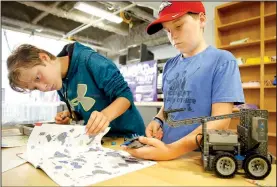  ?? NWA Democrat-Gazette/DAVID GOTTSCHALK ?? Kele Estes-Beard (left), 12, looks over the diagrams as Baydon Fuller, 13, collects parts for assembly Wednesday as they participat­e in the Fayettevil­le Robotics Summer Camp at Fayettevil­le High School. The four-day class uses the Vex IQ Robot platform.