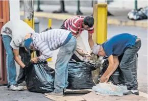  ?? AFP ?? Varias personas buscan comida en tanques de la basura, en una calle de Caracas.