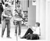  ?? WILFREDO LEE/ASSOCIATED PRESS ?? Law enforcemen­t officers talk to a man at FTL’s airport after a gunman killed 5 people in a January mass shooting.
