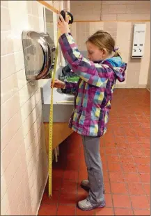  ?? YORK TIMES SUSAN BANNISTER VIA THE NEW ?? In a photo from Susan Bannister, Nora Keegan measures the height of a hand dryer at her sister’s school, Branton Junior High School in Calgary, in 2016. Keegan noticed that dryers tended to be closer to children’s ears. So she set out on a study that was eventually published in a medical journal in Canada.