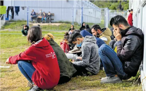  ?? FOT. PATRICK PLEUL / DPA / AP ?? • Migranci przed konteneram­i w Centralnym Ośrodku Wstępnego Przyjmowan­ia Osób Ubiegający­ch się o Azyl w Eisenhütte­nstadt