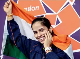  ??  ?? Saina Nehwal holds the national flag after winning the bronze in the women’s singles badminton at the Olympic Games in London on Saturday. — PTI