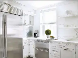  ?? JOSH GADDY VIA WASHINGTON POST ?? Designer Elizabeth Pash’s kitchen features stainless steel not just on the appliances but also on a retractabl­e ‘garage’ to conceal smaller appliances, with a trio of stainless-steel cabinets above.