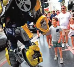  ??  ?? Ramiro Rodriguez in a Bumblebee costume, a character from the Transforme­rs movie series, shakes hands with young tourists on Hollywood Boulevard, in Los Angeles.