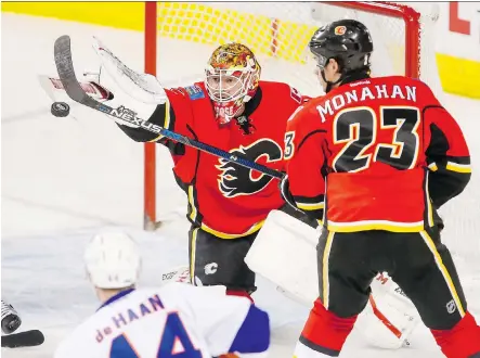  ?? LYLE ASPINALL ?? Flames goalie Brian Elliott swats the puck near Sean Monahan during Sunday’s 5-2 win over the New York Islanders.