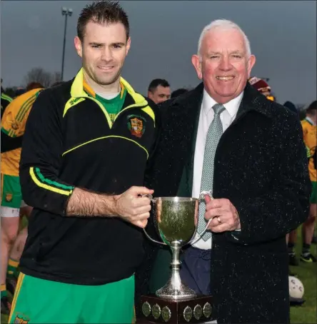  ??  ?? East Kerry Board Chairman Johnny Brosnan presenting Gneeveguil­la team captain Patrick Riordan with the Fr Gavin Cup after his team beat in the East Kerry Intermadat­e Championsh­ip Final