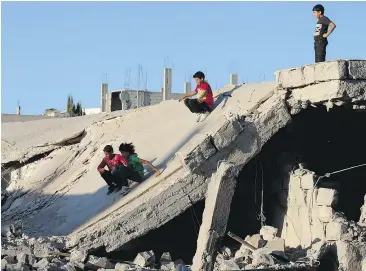  ?? — GETTY IMAGES ?? Children slide down rubble in the rebel-held city of Daraa, in Syria on Monday. A ceasefire in the Syrian conflict was due to take effect at 7 p.m. Monday.
