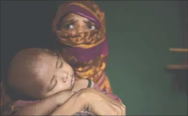  ?? The Associated Press ?? A Rohingya Muslim holds her baby boy as she sits in her shelter in a refugee camp in Bangladesh.