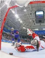  ?? THE ASSOCIATED PRESS ?? U.S. women’s hockey player Jocelyne Lamoureux-Davidson, left, watches as the puck slides past Canadian goalie Shannon Szabados for the winning goal in a 3-2 shootout victory in the gold medal final Thursday at the Winter Olympics.