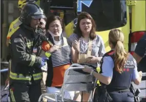  ?? THE ASSOCIATED PRESS ?? Injured people are treated in Barcelona, Spain on Thursday after a white van jumped the sidewalk in the historic Las Ramblas district, crashing into a summer crowd of residents and tourists and injuring several people, police said.