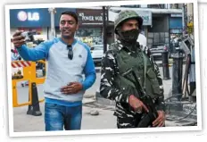  ?? ?? a tourist takes a selfie with an Indian paramilita­ry trooper standing guard along a street in srinagar.