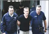  ??  ?? In this file photo, police officers escort Alexander Vinnik (center), as they leave a courthouse at the northern Greek city of Thessaloni­ki. The Russian bitcoin fraud suspect Alexander Vinnik goes on trial on Monday in Paris. (AP)
