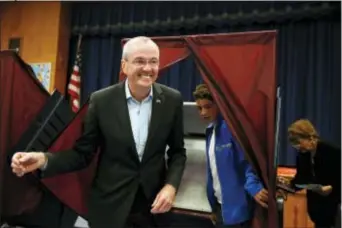  ?? BOB KARP — THE DAILY RECORD VIA AP ?? Democrat Phil Murphy exits the polling booth with his youngest son Sam, after voting at the Fairview School on Tuesday in Middletown.