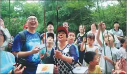 ?? PROVIDED TO CHINA DAILY ?? Hangzhou citizens learn how to catch cicadas with Jin Sucui (center with red cap) at a park in the capital city of Zhejiang province.