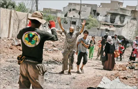  ?? REUTERS ?? An Iraqi man (C) is ordered to raise his hands for a check as civilians displaced by fighting between the Iraqi forces and ISIS flee the al-Zanjili district in Mosul, Iraq on Saturday.