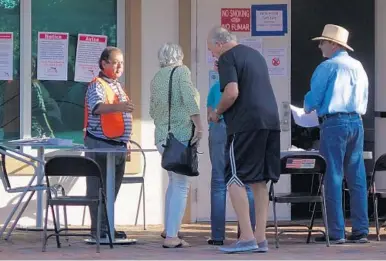  ?? JOE CAVARETTA/SUN SENTINEL ?? Voters are greeted by election officials at the Boca Raton Library on Monday, the first day of early voting in Florida.
