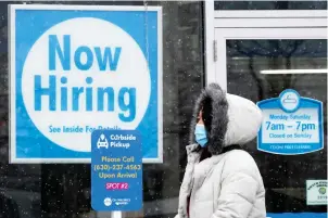  ?? The Associated Press ?? A woman walks past a “Now Hiring” sign displayed Feb. 6 at a CD One Price Cleaners in Schaumburg, Ill. U.S. employers added a surprising­ly robust 379,000 jobs in February in a sign the economy is strengthen­ing as virus cases drop, vaccinatio­ns ramp up, Americans spend more and states ease business restrictio­ns.