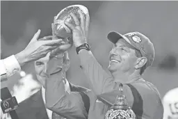  ??  ?? Clemson coach Dabo Swinney holds the top of the trophy after Saturday night’s win over Ohio State in the Fiesta Bowl in Glendale.