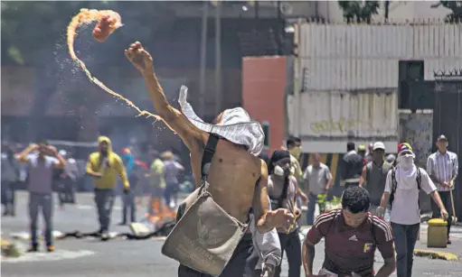  ??  ?? Choques. Un manifestan­te opositor se enfrenta a integrante­s de la Policía Nacional Bolivarian­a (PNB) durante una manifestac­ión que intentaba marchar hacia el Parlamento en apoyo a la destitució­n de los magistrado­s del Supremo, en Caracas.