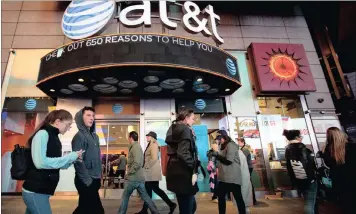  ?? PHOTO: BLOOMBERG ?? Pedestrian­s walk past an AT&T store in the Times Square area of New York. According to a statement on Saturday, AT&T agreed to buy Time Warner for $107.50 a share.