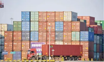  ??  ?? A truck transports a shipping container at Qingdao port in Shandong province, China. Reuters