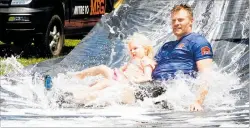  ??  ?? Wanganui rugby representa­tive Simon Dibben takes his daughter down the slide as he competes in the parents, teachers and adults race at the end of the afternoon.