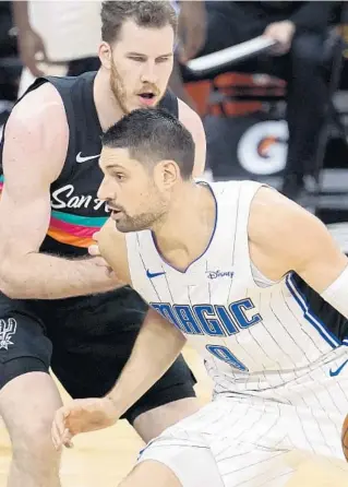  ?? ERIC GAY/AP ?? Magic center Nikola Vucevic, who finished with 26 points, drives around Spurs center Jakob Poeltl during the first half on Friday night in San Antonio.