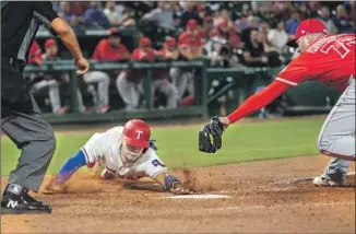  ?? Jeffrey McWhorter Associated Press ?? TEXAS RANGERS’ Robinson Chirinos scores ahead of the tag from Angels reliever Osmer Morales on a wild pitch during the eighth inning. Texas scored three runs in the inning.