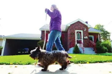  ?? VINCE TALOTTA/TORONTO STAR ?? Peggy Hay walks past a neighbour’s home in Port Hope that was decontamin­ated at a cost of nearly $500,000.