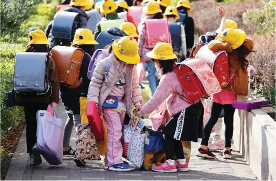  ??  ?? Elementary school students carry their belongings as they make their way home in Tokyo. The expectatio­n that Japan would close all its elementary, secondary and high schools will send nearly 13 million children home. Photo: AP