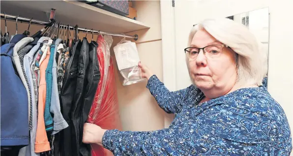  ?? ?? At the end of her tether
Heather Todd, at her damp-ridden council home, holding a specialist device which she uses to protect her clothes from the damp