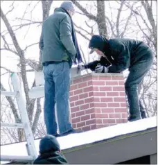  ?? Photograph by Tom Throne ?? Neal Sizemore, right, of Top Hat Services of Springdale, does a visual inspection of a flue on a house in Bella Vista. Assisting him is Justin Sizemore, on the ladder, and Jake Cromwell.