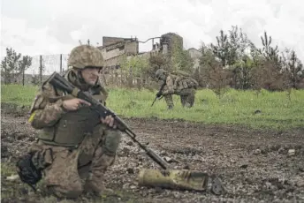  ?? MSTYSLAV CHERNOV/AP ?? Ukrainian servicemen squat during a patrol in a recently retaken village north of Kharkiv, east Ukraine, on Sunday.